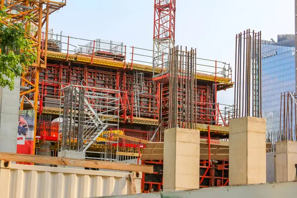 Modern bir yapı inşa etmenin erken aşamalarını gösteren yapı iskelesi ve beton biçimlere sahip büyük bir inşaat alanı..