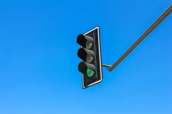 Şehir ortamında mavi gökyüzüne karşı yeşil sinyali olan şehir trafik lambası sistemi