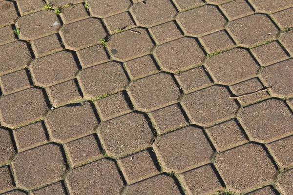 Yıpranmış kaldırım taşı yüzeyi detaylı doku kalıplarını ve geleneksel taş sokak malzemelerinin doğal yaşlanmasını gösteriyor.