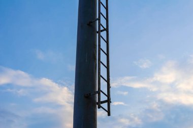 Mavi gökyüzüne karşı beyaz bulutlu uzun metal iletim kulesi yapısı