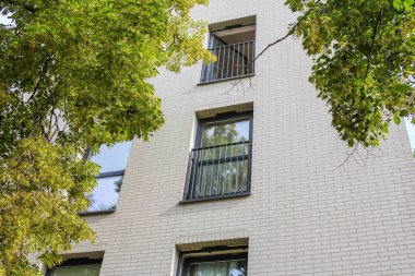 Gündüz vakti birden fazla pencere ve balkon olan çağdaş apartman cephesi