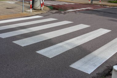 Koyu asfalta boyanmış beyaz çizgili yaya geçidi geometrik desen oluşturur