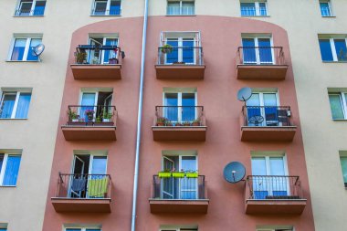 Mavi balkonlu ve geleneksel Avrupa mimari tarzlı çok katlı bir bina.