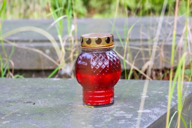 Anma töreni için mezar taşı üzerinde altın tutacağı olan kırmızı cam bir anıt mum.