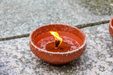 Tek kil yağ lambası ve parlak alevler dokulu taş yüzeyde yanıyor.