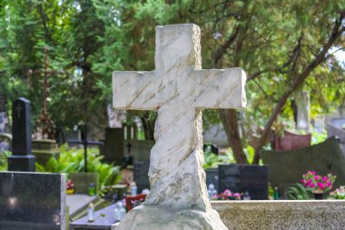 Beyaz taş mezarlık mezar taşı yeşil ağaçların arasına yerleştirilmiş. Yaz mezarlığında huzurlu bir anıt alanı oluşturuyor.