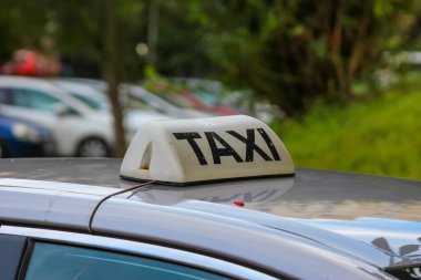 Şehir ortamında taksi hizmetini gösteren sarı taksi tabelası arabanın çatısında aydınlandı