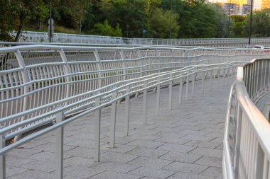 Şehir ortamında metal ağ parmaklıkları ve beton yüzeyi olan modern yaya köprüsü geçidi