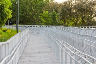 Metal örgülü uzun yaya köprüsü yolu yeşil araziye doğru doğrusal perspektif oluşturuyor