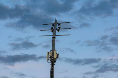 Telekomünikasyon anten kulesi akşam saatlerinde karamsar atmosferik aydınlatma ile dramatik bulutlu gökyüzüne karşı siluetlendi