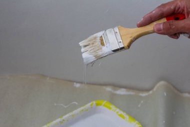 İç duvar yenileme projesi sırasında beyaz boya uygulayan profesyonel boya fırçası.