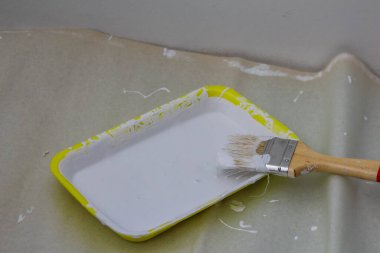 Beyaz boyalı sarı boya tepsisi ve paten fırçası tadilat ve duvar boyası için hazır.