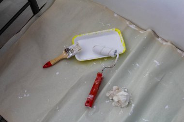 Aktif ev yenileme projesi sırasında sarı tepside kırmızı saplı boya ve fırça