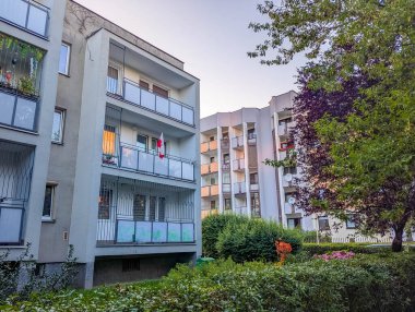 Çağdaş konut kompleksi, birden fazla balkon ve modern mimari, olgun ağaçlarla çevrili.