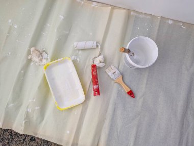 Beyaz silindirli boya tepsisi ve ev yenileme projesi için düzenlenmiş çeşitli boyama araçları