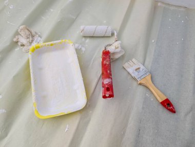 Beyaz boya tepsisi ve koruyucu plastik kaplama üzerine yerleştirilmiş aletlerle profesyonel boya kurulumu