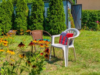 Kırmızı sulama renkli bir yaz bahçesinde canlı çiçekli bitkiler arasında konulabilir.