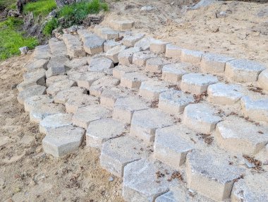 İnşaat sahasında sistematik olarak istiflenmiş büyük gri beton bloklar inşaat projelerine hazır.