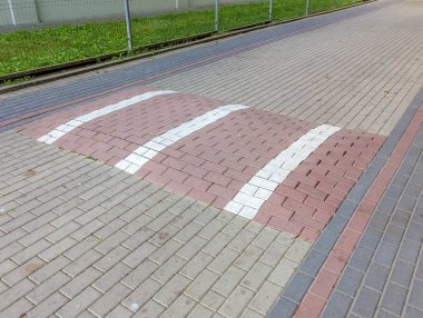 Beyaz çizgili tuğla kaldırım geçidi şehir caddesinde geometrik desen oluşturuyor.