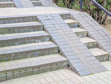 Dış duvar boyunca uzanan metal parmaklıkları olan uzun beton merdiven.