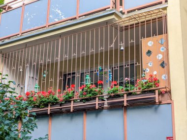 Ahşap balkon korkuluklu modern iskan binası gün ışığında sakin suya yansıyor.