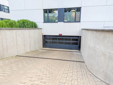 Contemporary residential building entrance with modern concrete architecture and paved driveway featuring clean geometric design