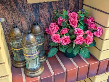 Fresh pink roses arrangement with memorial candles displayed on granite cemetery surface for tribute ceremony