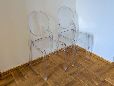 Minimalist iç uzayda ahşap ringa kemiği zeminine yerleştirilmiş tek beyaz modern sandalye.