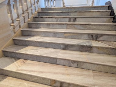 Wide view of modern stone staircase with geometric pattern steps ascending in contemporary building interior