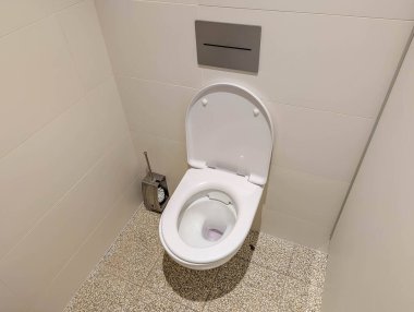 Modern tasarımı olan beyaz seramik klozet temiz banyo içinde döşeme döşenmiş.