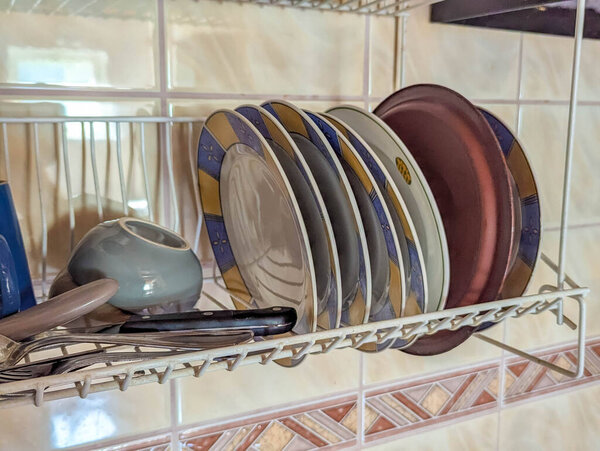 Kitchen dish drying rack filled with plates and cookware in organized domestic setting