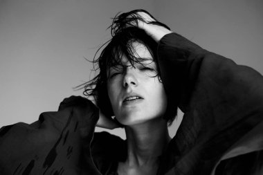 Genç insanın yüzünde dramatik ışıklandırma ve gölgelerin yer aldığı tek renkli yakın plan portre.