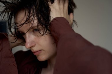 Saçları dağınık, bordo süveter giyen, yumuşak, doğal ışıklandırmalı genç bir adam.