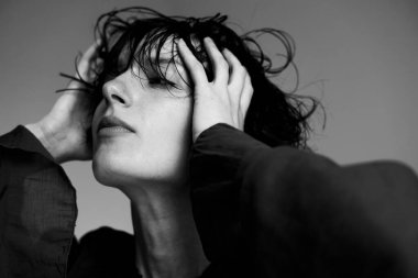 Islak saçlı ve elleri anlamlı bir pozda kaldırılmış siyah beyaz bir portre.