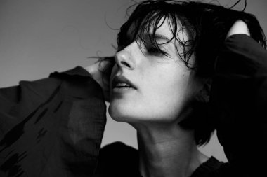 Islak saçlar, dramatik gölgeler, sanatsal kompozisyon ve aydınlatma içeren tek renkli yakın plan portre.