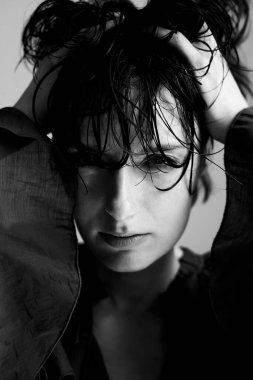 Monokrom portresi, ıslak saçlı, derin düşüncelere dalmış dramatik ışıklandırmayla bakan birini gösteriyor.