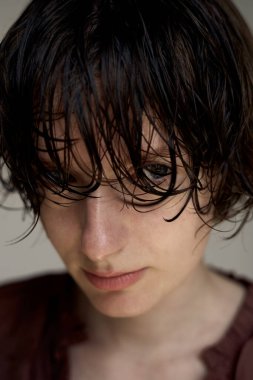 Burgonya rengi kazaklı, ıslak saçlı genç adam yakın plan portresiyle yakalandı.