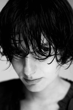 Islak saçlı ve dramatik bir kontrastlık gösteren siyah beyaz bir genç portresi.