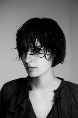 Sanatsal kompozisyon ve aydınlatma ile desenli koyu renk elbiseli genç kişinin monokrom portresi