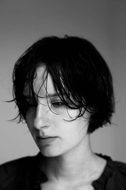 Islak saçlı, dalgın dalgın bakışlı birinin siyah beyaz portresi.