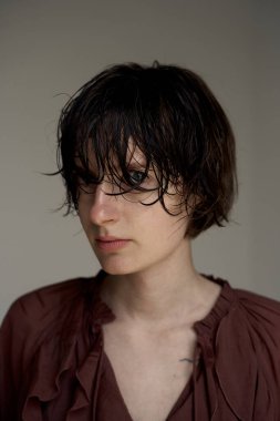 Burgonya rengi saçı olan genç birinin portresi yumuşak doğal ışıklandırmayla dalgalanıyor.