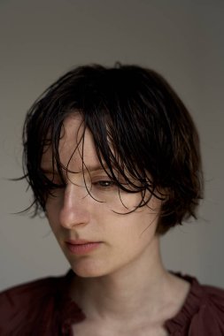 Islak saçlı, bordo kazaklı genç adam dalgın dalgın bakıyor.