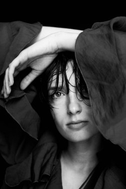 Siyah beyaz kapüşonlu kadın portresi. Yüzünün yakınına yerleştirilmiş, dalgın bir ruh hali sergiliyor.