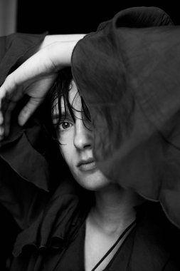 Kapüşonlu kadının tek renkli portresi. Sanatsal gölge oyunu ve kontrast ile öne eğiliyor.