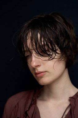 Burgonya rengi bluzlu, saçları dağınık genç bir kadının portresi doğal güzelliği gösteriyor.