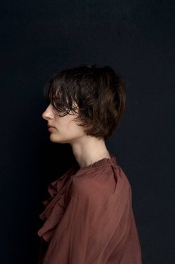 Burgundy süveter giyen genç bir kadının portresi. Düşünceli bir ifadeyle yana bakıyor.