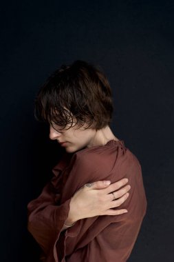 Burgundy kazaklı genç bir kadının portresi. Şefkatli bir kişisel bakım jesti ile kendine sarılıyor.