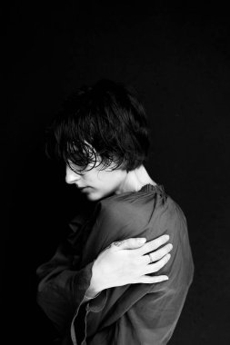 Kendini kucaklayan tek renkli kadın portresi sanatsal kompozisyonda kırılganlık ve güç gösteriyor.