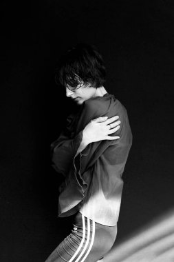 Çizgili kapüşonlu, minimalist atletik moda tarzlı siyah beyaz kadın portresi.