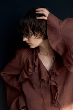 Burgonya renginde fırfırlı bluzlu bir kadın portresi. Elleri kafaya kadar dalgın bir şekilde kaldırılmış.